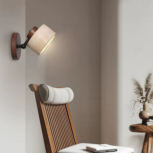 Travertine drum wall sconce angled toward a reading chair