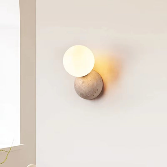 Stone dome wall sconce with a frosted glass globe, lit, beside an arched window.