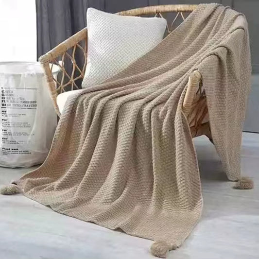 Camel waffle knit throw draped over a rattan chair.
