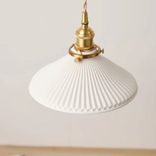 Close view of the white pleated shade and copper-finish holder of the pendant light, unlit.