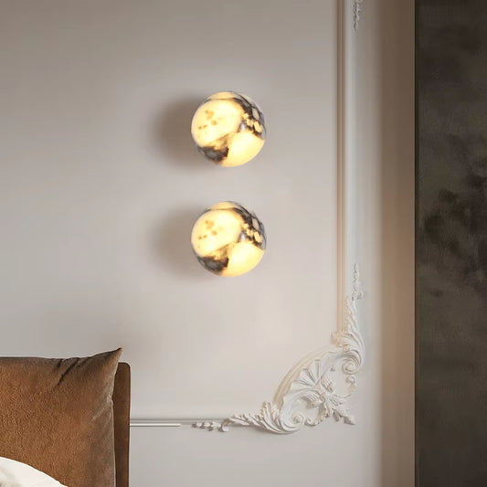 Two marble sphere wall sconces, lit, one above the other on a white wall.
