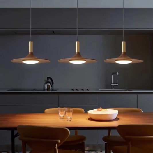 Three flying saucer pendant lights in a row over a dining table.