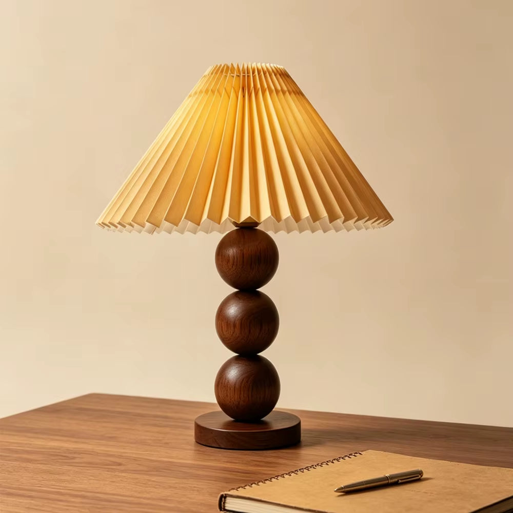 Walnut-color stacked-sphere table lamp with a walnut-toned pleated shade on a desk.