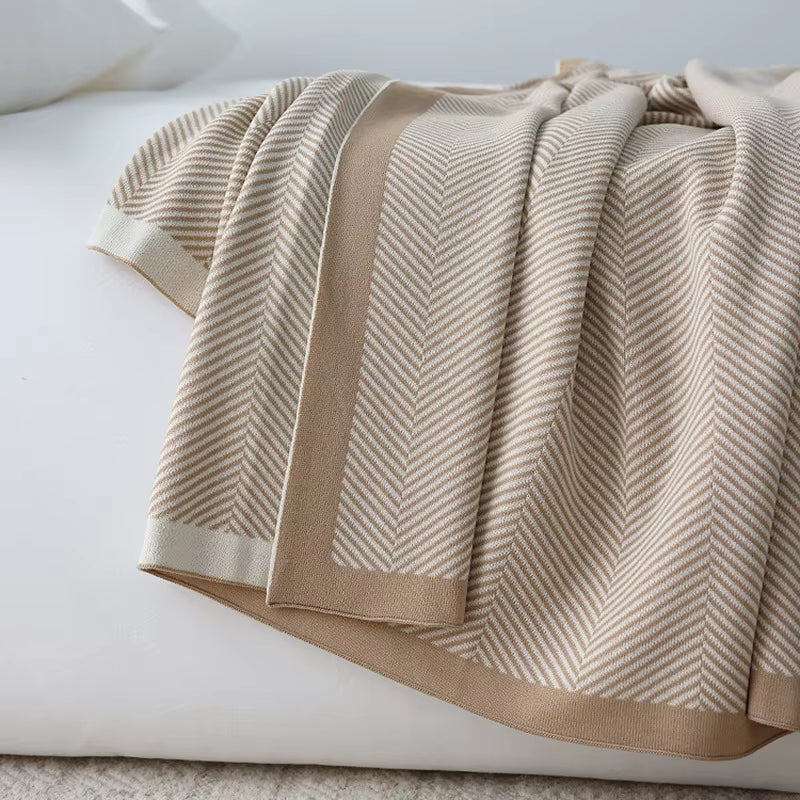 Khaki herringbone knit throw blanket with a wide border, draped in folds.