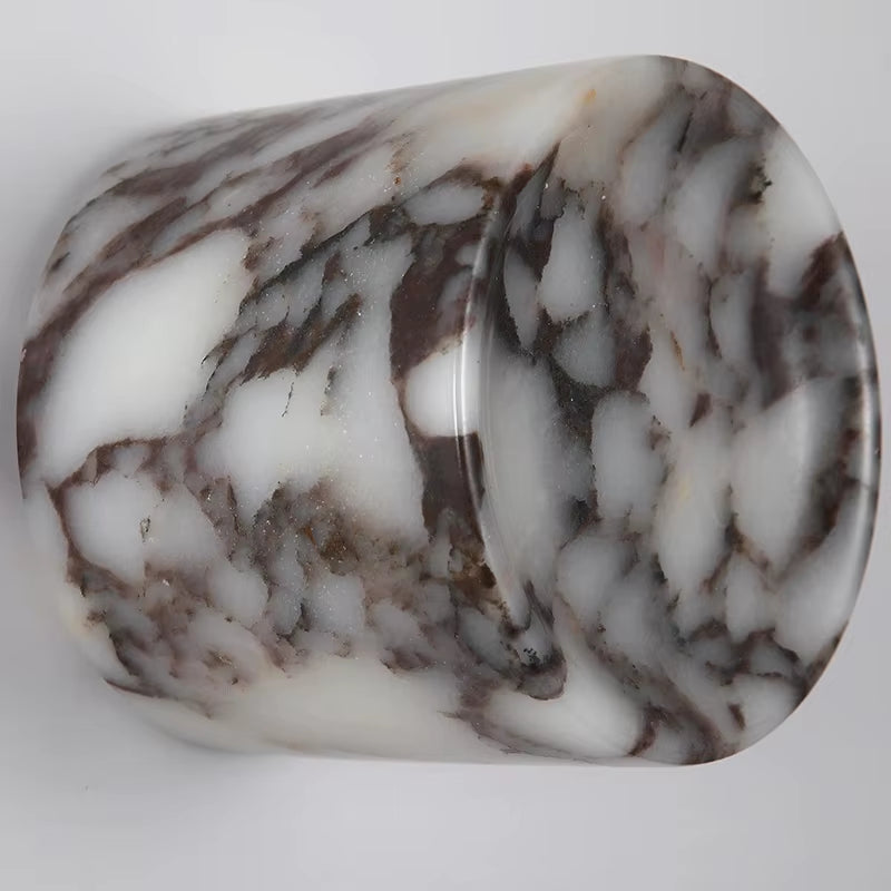 Close view of the marble cylinder wall sconce, unlit, showing the dark veining in the white stone.
