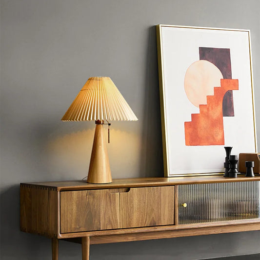 Natural wood cone table lamp with a pleated fabric shade on a wooden console.