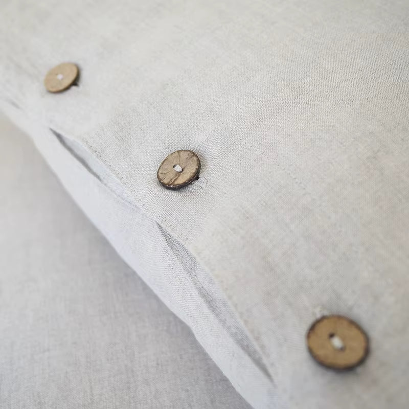 Close view of wooden buttons on a natural linen pillow cover.