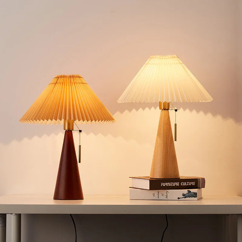 Walnut and natural wood cone table lamps with pleated shades, lit.