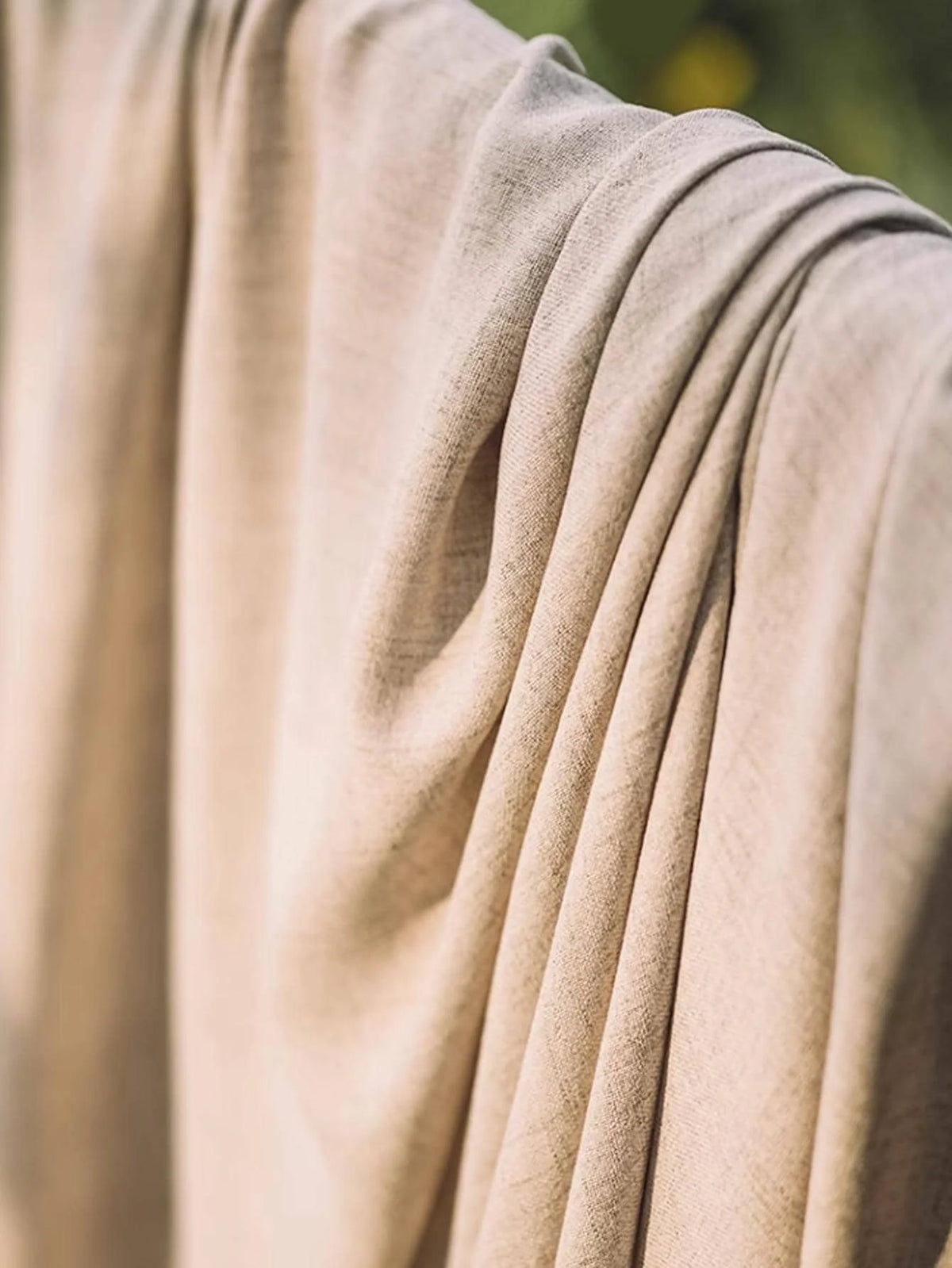 Close view of the natural beige cotton-linen curtain fabric in folds.