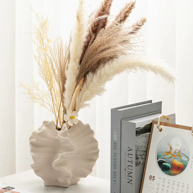 Cream wave vase with pampas grass by a bookshelf