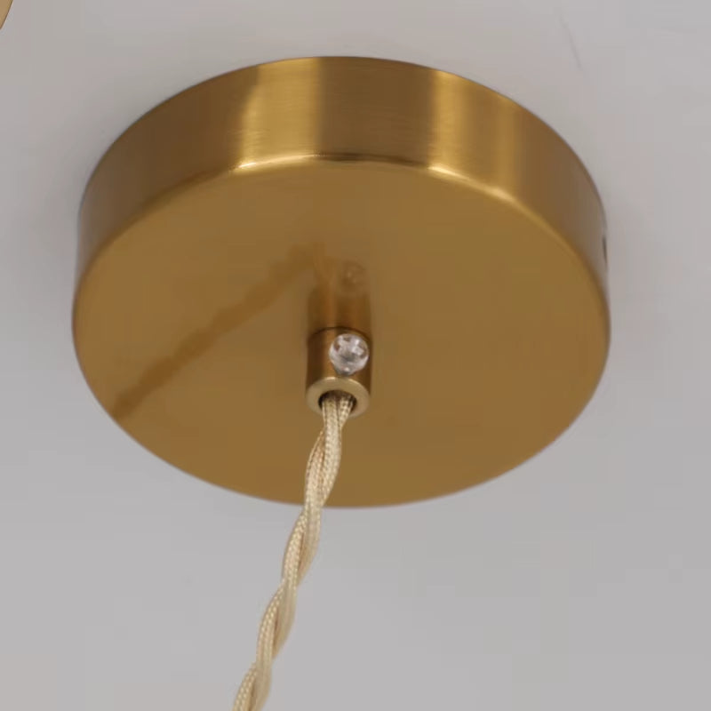 Round copper-finish ceiling plate of the pendant light with its twisted cord.