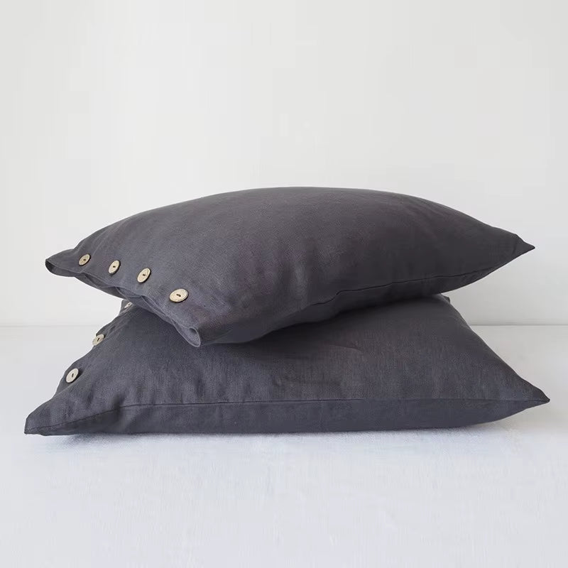 Two dark grey linen pillow covers with button closures, stacked.