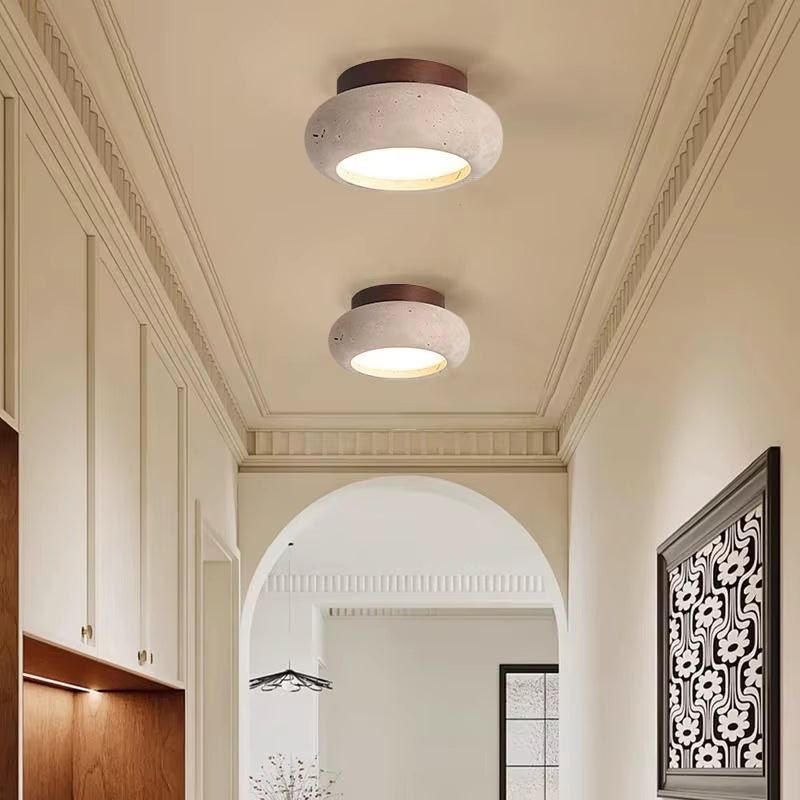 Two rounded travertine ceiling lights with dark wood canopies lit in a hallway
