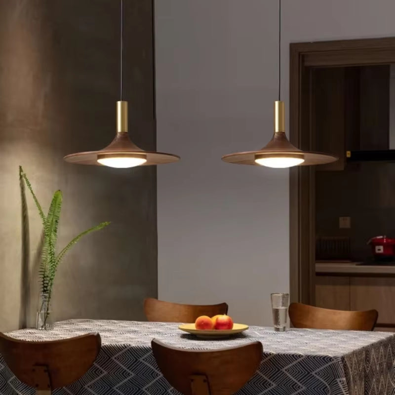 Two flying saucer pendant lights over a dining table.