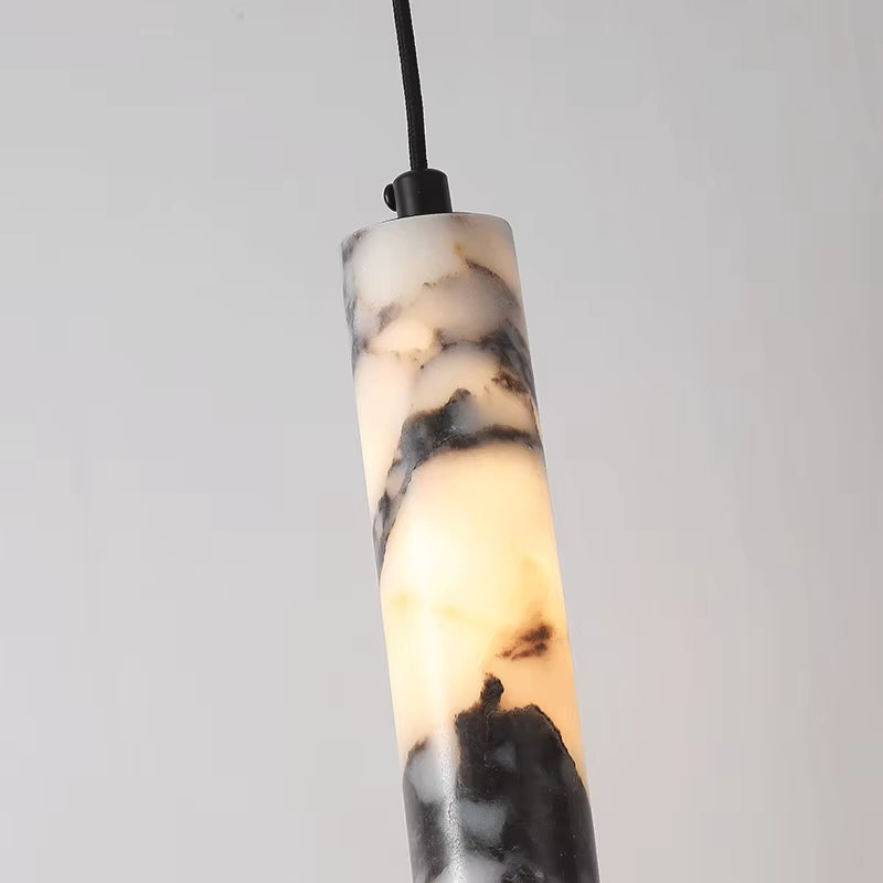 Close view of the top of the slim marble cylinder pendant, showing the black cord fitting and the veining.