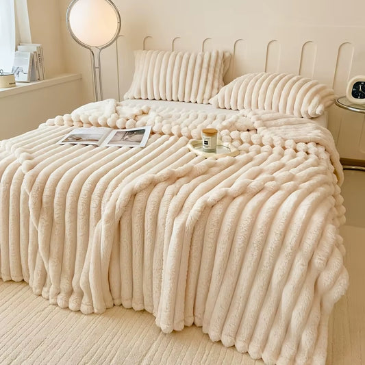 Ivory ribbed faux fur throw spread across a bed with matching ivory bedding.