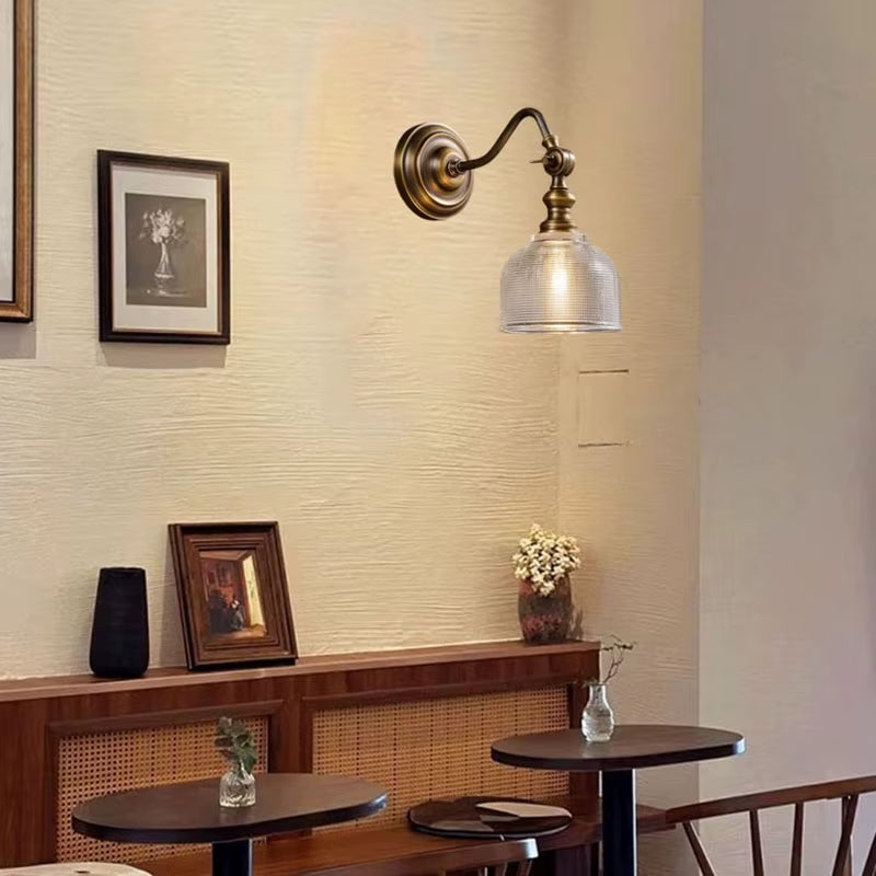 Brass wall sconce with ribbed glass shade and curved arm