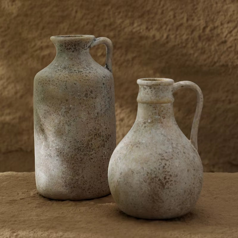 Two rustic ceramic jug vases with a weathered stone-grey finish, the tall jug and the round jug side by side.