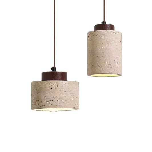 Two travertine cylinder pendant lights, one short and one tall, each with a walnut-tone cap.