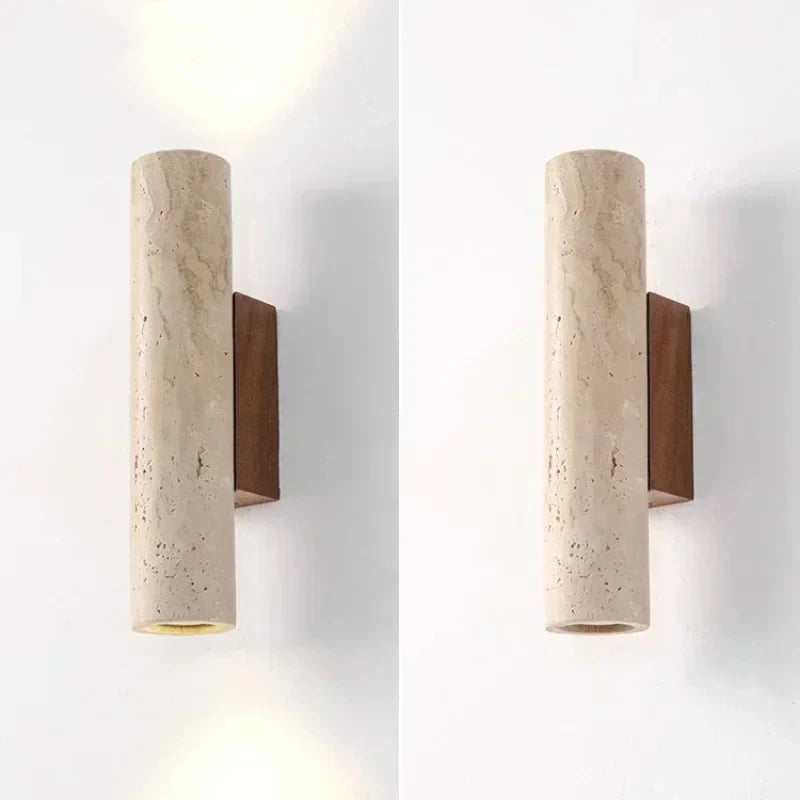 Travertine cylinder wall sconce with walnut wood bracket shown from two angles on a white wall.