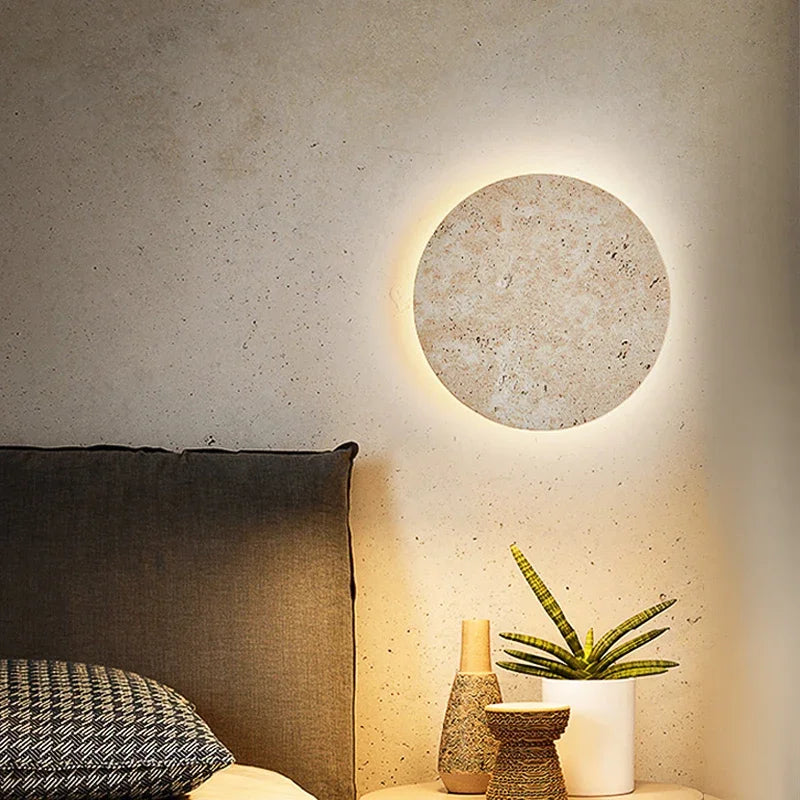 Stone disc wall sconce beside a bed