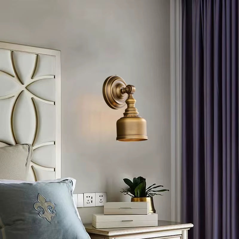 Brass-shade wall sconce beside a bed