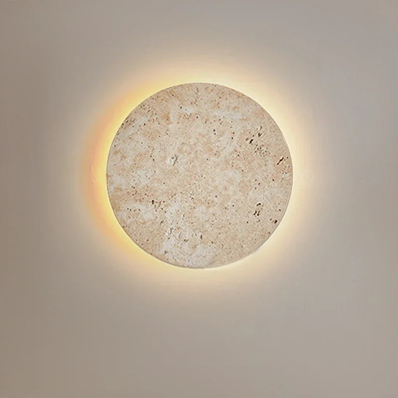 Round natural stone wall sconce with a warm halo of light