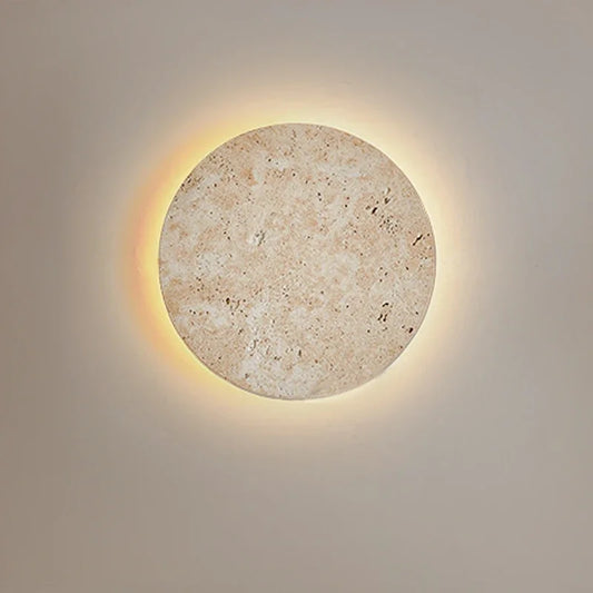 Round natural stone wall sconce with a warm halo of light
