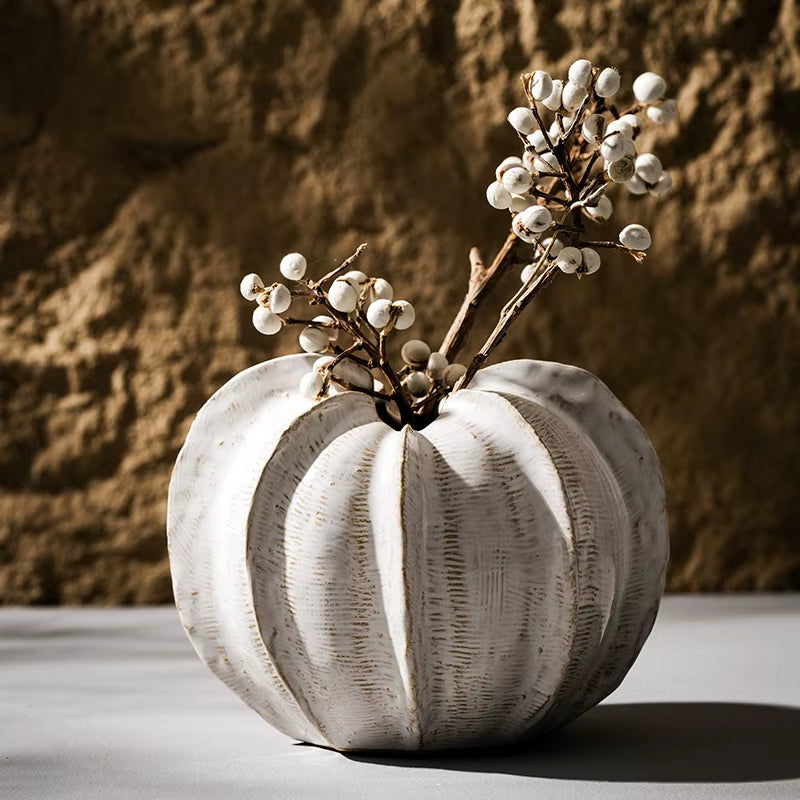 Round ribbed ceramic pod vase holding a sprig of white berries.