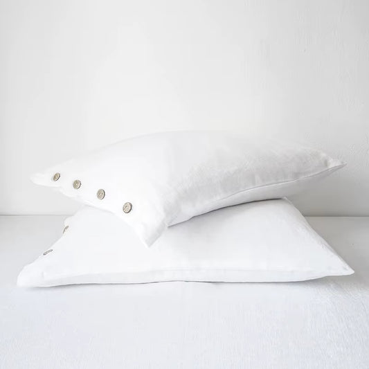 Two white linen pillow covers with button closures, stacked.