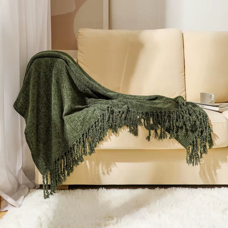 Army green chenille throw blanket draped over the arm of a cream sofa.