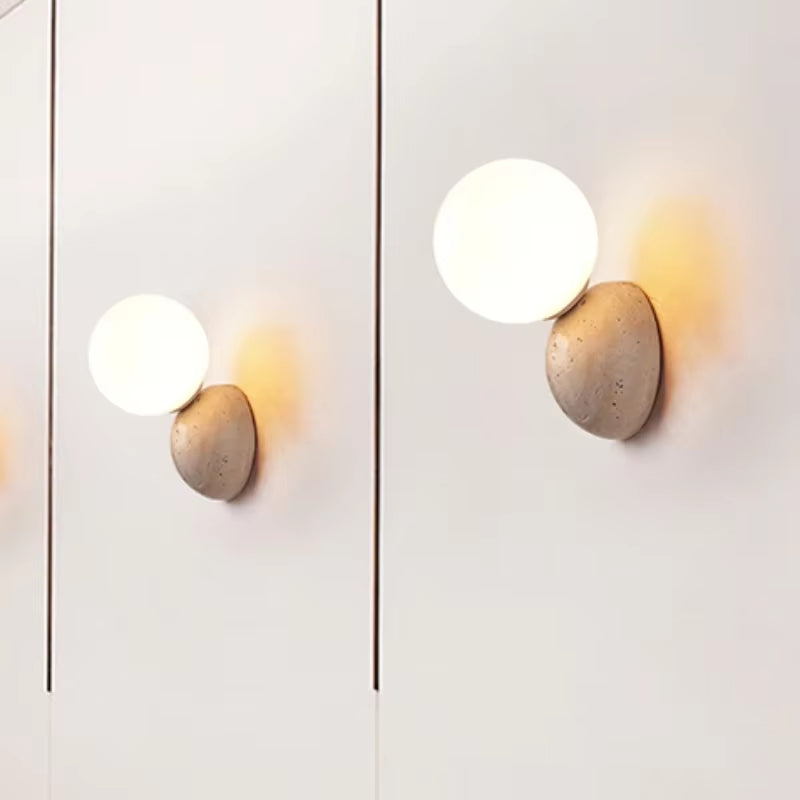 Two stone dome wall sconces with frosted glass globes, seen from two angles on a pale wall.