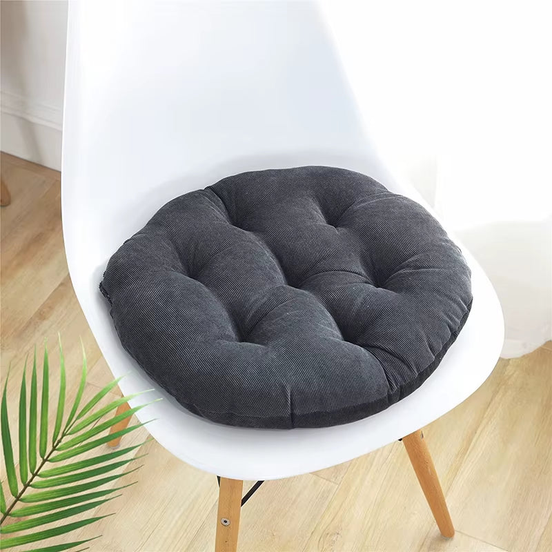 Round dark grey corduroy seat cushion on a white chair.
