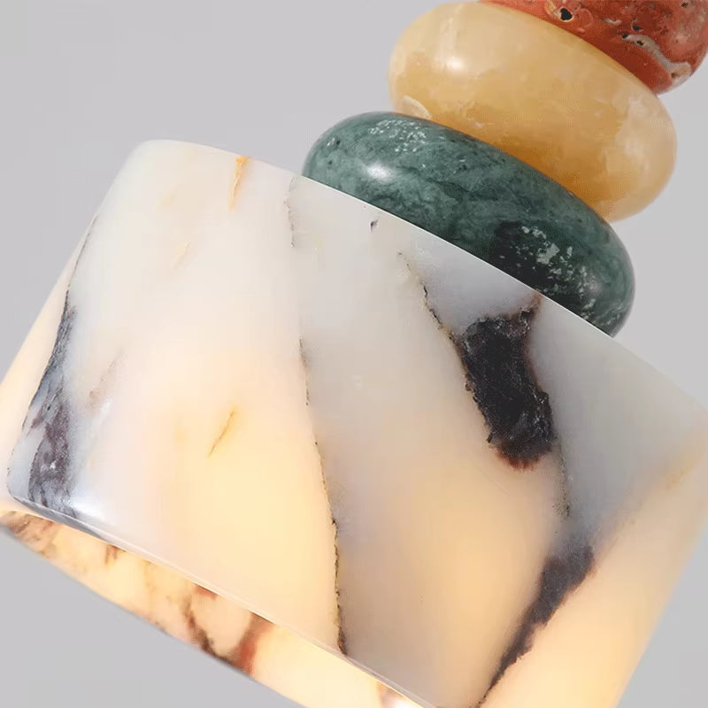 Close view of the veined stone drum, lit, with the green and yellow stone discs above it.