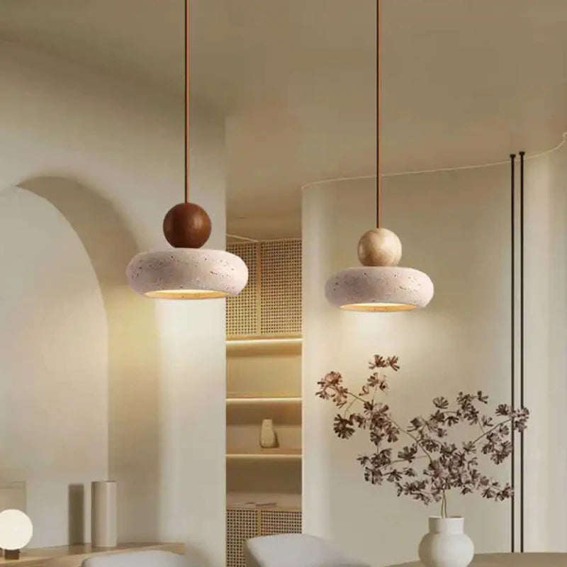 A walnut-color and a log-color pendant light hanging side by side in a white room.