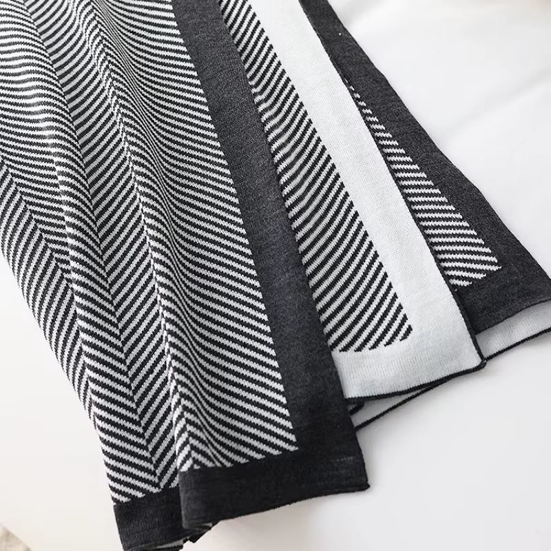 Black herringbone knit throw folded to show its contrast border.