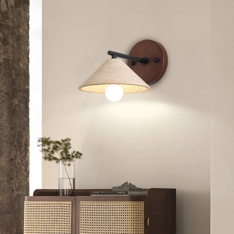 Travertine cone wall sconce lit above a cabinet