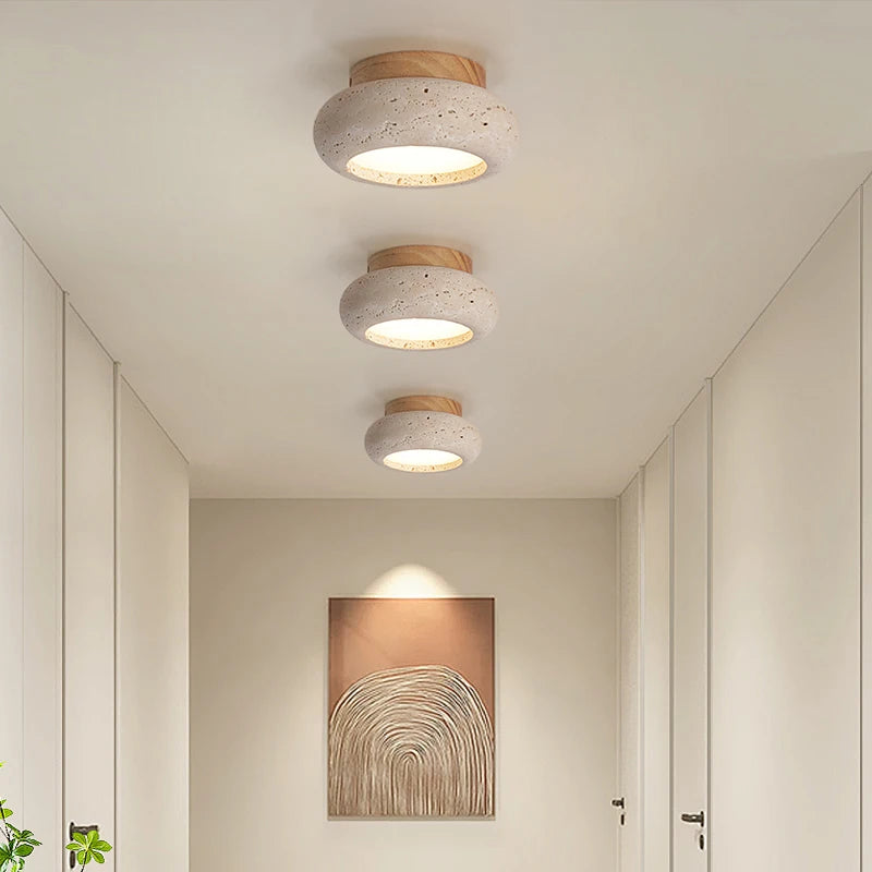 Three rounded travertine ceiling lights with light wood canopies along a corridor