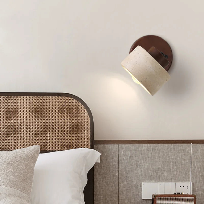 Travertine drum wall sconce angled above a bed