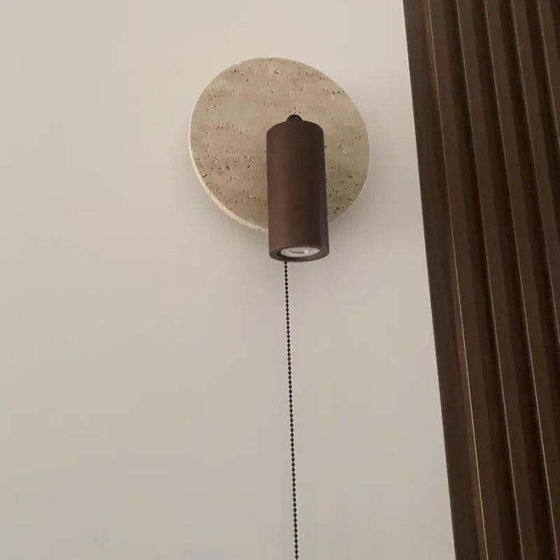 Travertine disc wall sconce with the spotlight pointing down and the pull chain hanging