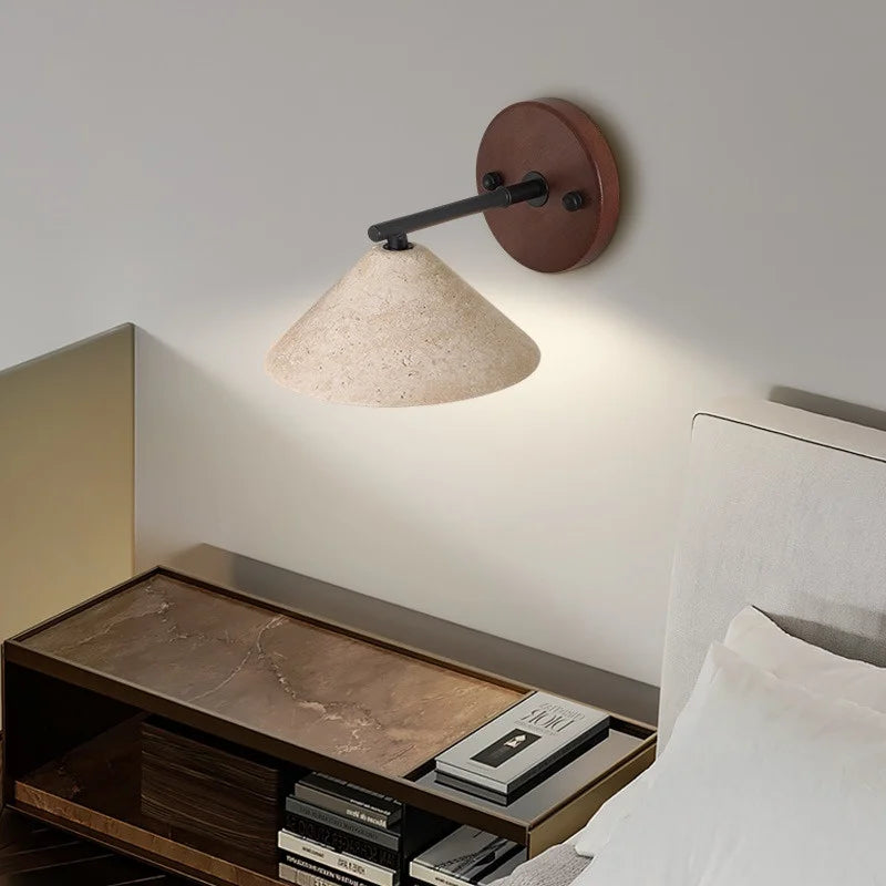 Travertine cone wall sconce above a bedside table