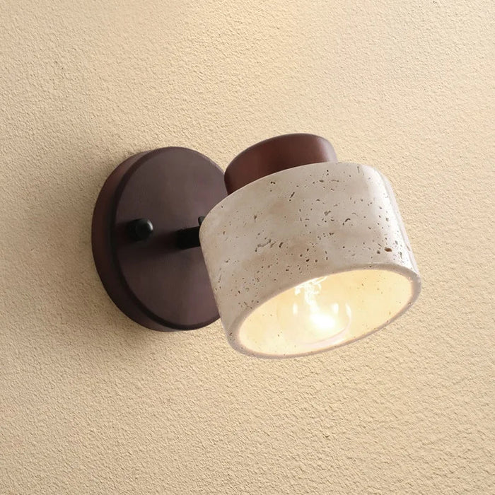 Travertine drum wall sconce tilted on a dark wood backplate, close view