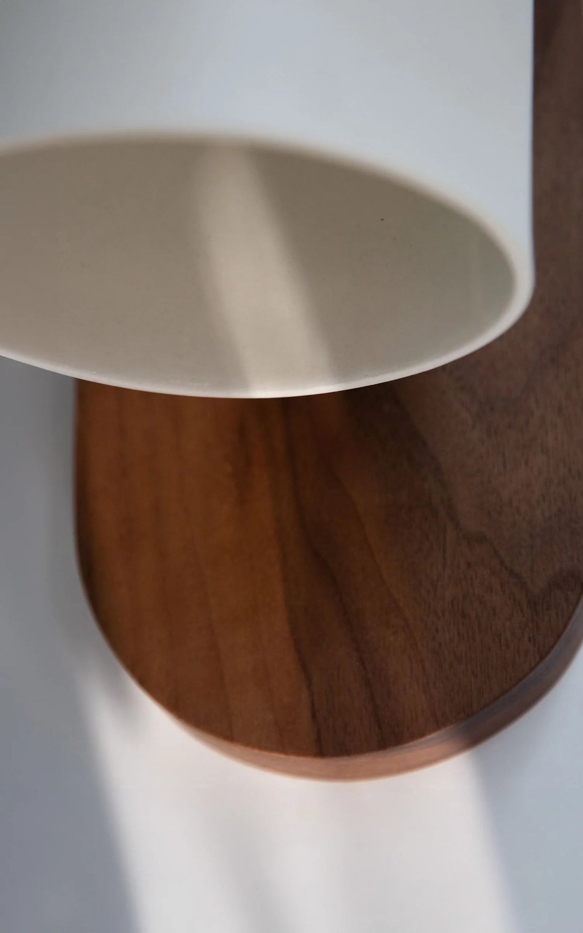 Close view of the white shade rim and the walnut-color wood backplate