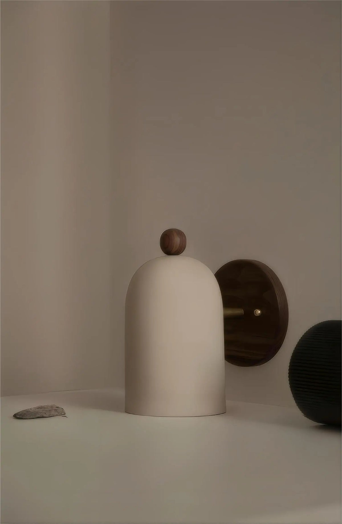 Round backplate wall sconce with a white bell shade standing on a table