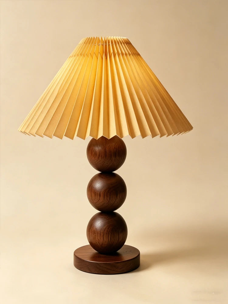 Walnut-color stacked-sphere table lamp with a walnut-toned pleated shade, lit, on a plain background.