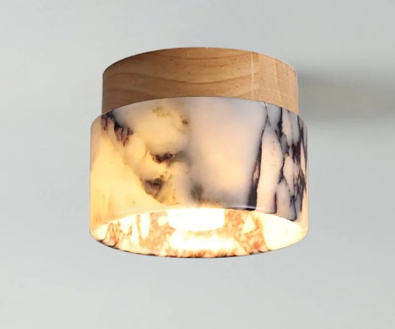 Close view of the lit marble shade and light wood canopy of the flush mount ceiling light