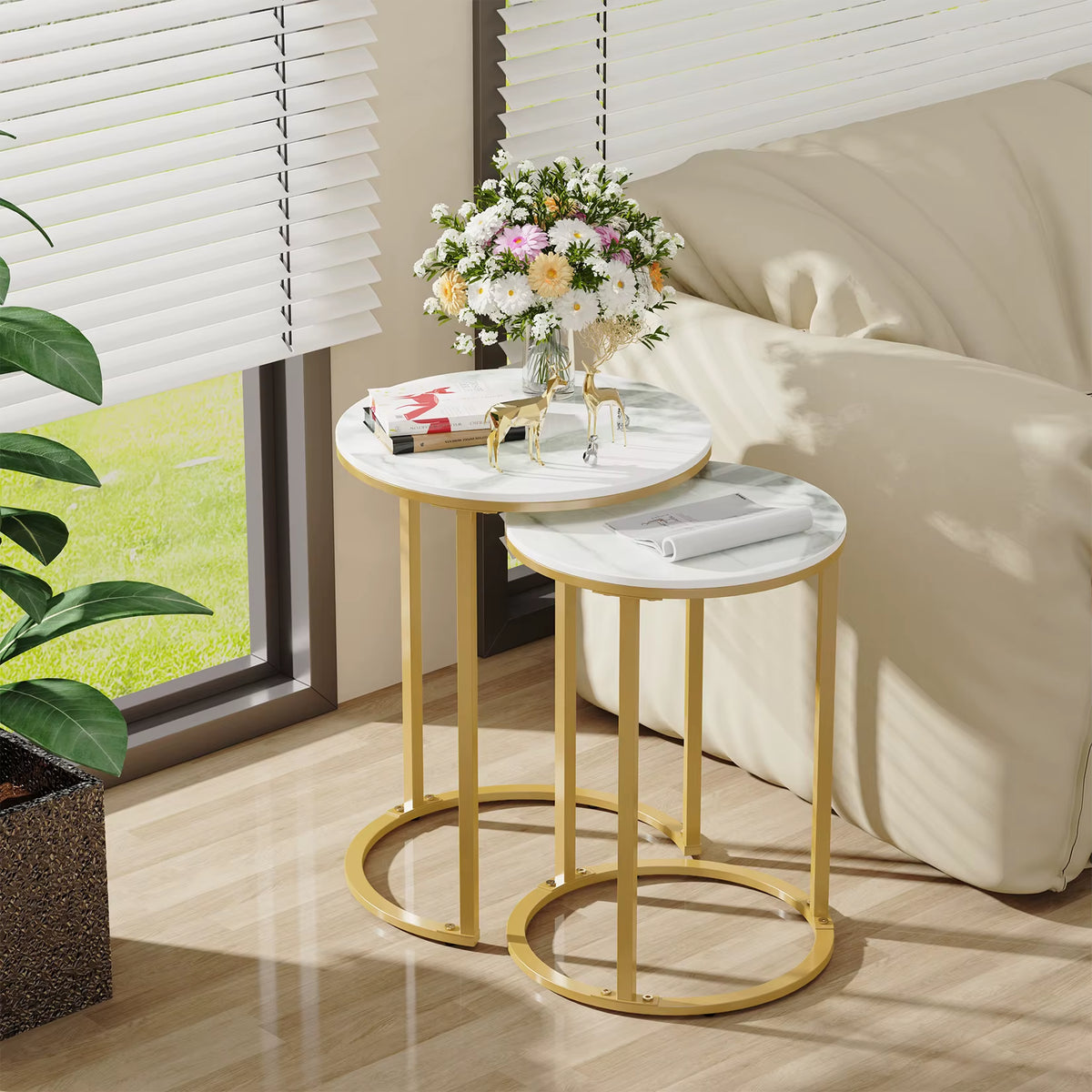 Two round nesting side tables with white tops and gold metal frames beside a cream sofa.