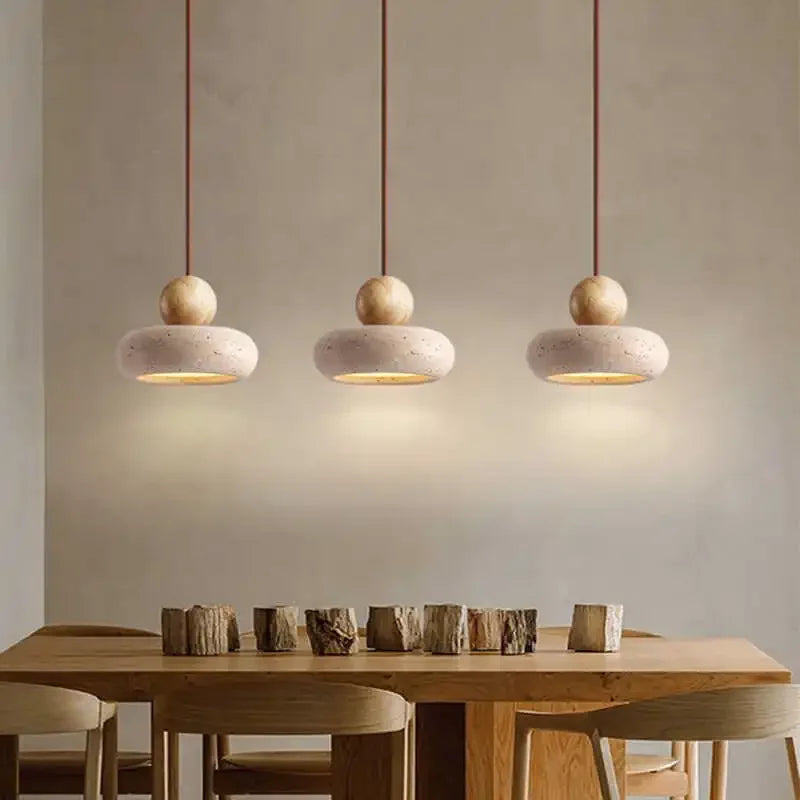 Three log-color pendant lights hanging in a row over a wooden dining table.