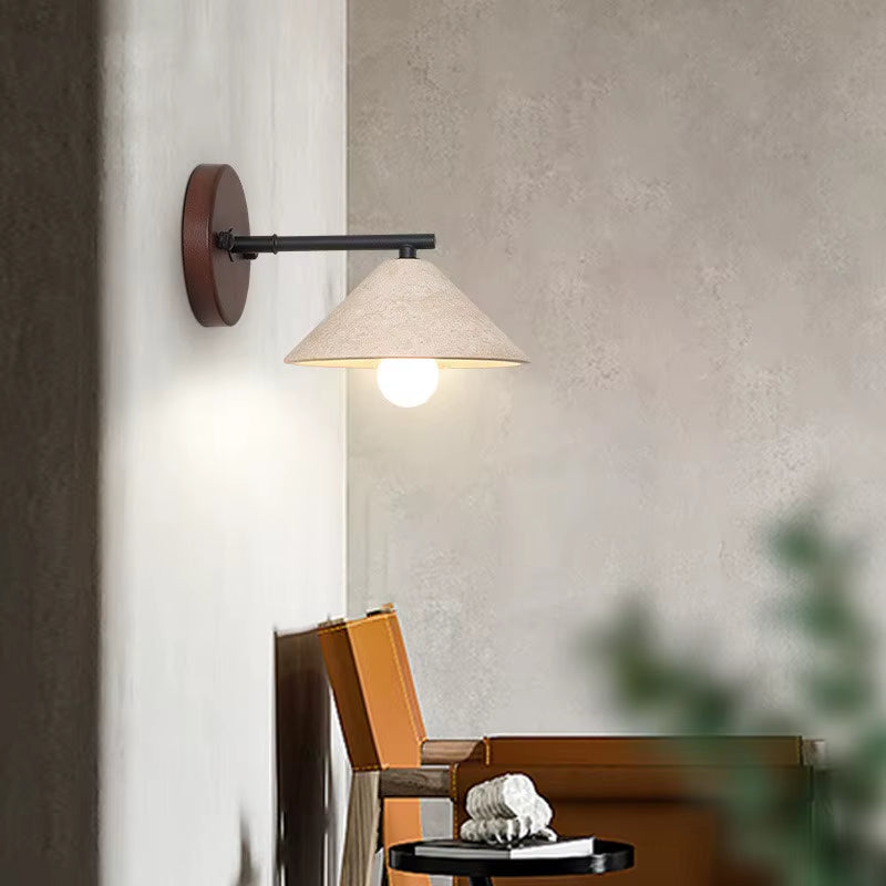 Travertine cone wall sconce seen from the side, lit