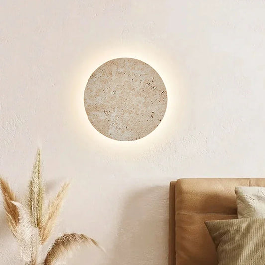 Stone disc wall sconce above a sofa